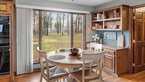 Une cuisine avec une table à manger, des chaises et une vue sur l’extérieur.