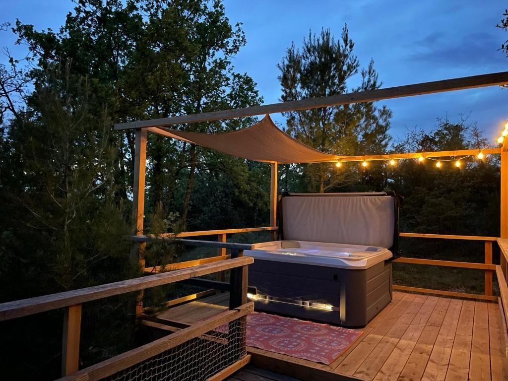 A hot tub on a wooden deck with a canopy and string lights.