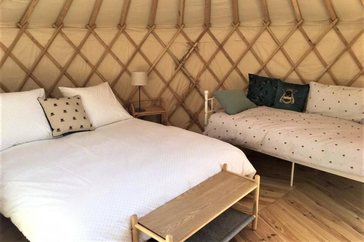 Interior acogedor de una yurta con dos camas, una mesita y una lámpara.