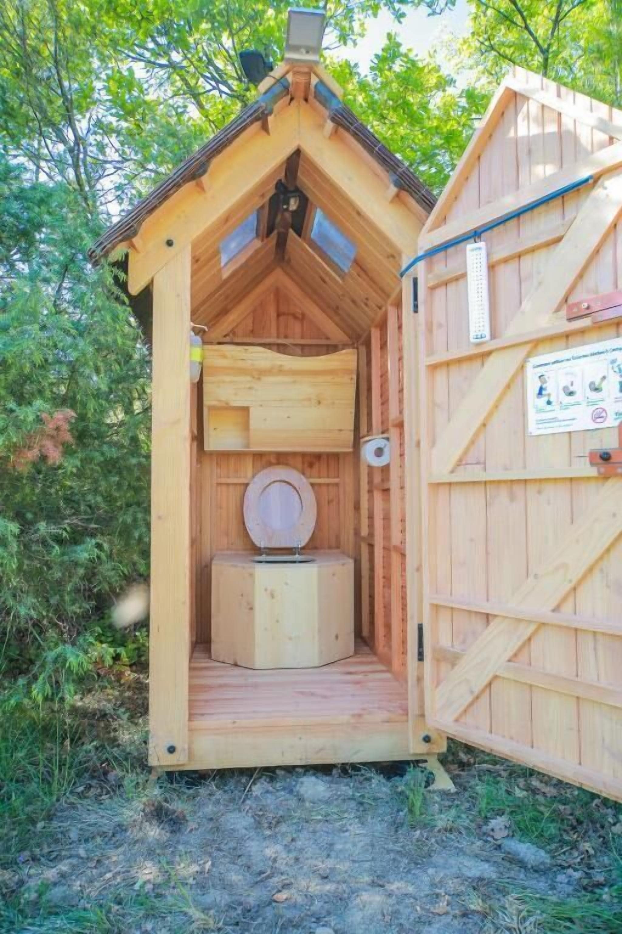 Een houten bukken met een schuin dak, een toilet en een klein plankje.