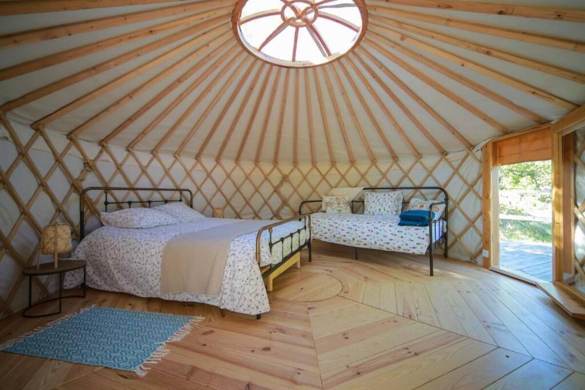 Una yurtas con dos camas, una claraboya circular y suelo de madera.
