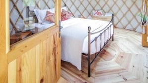 A yurt with a bed, a wooden door, and a circular skylight. - Les Yourtes de Provence (Saint-Paulet-de-Caisson)