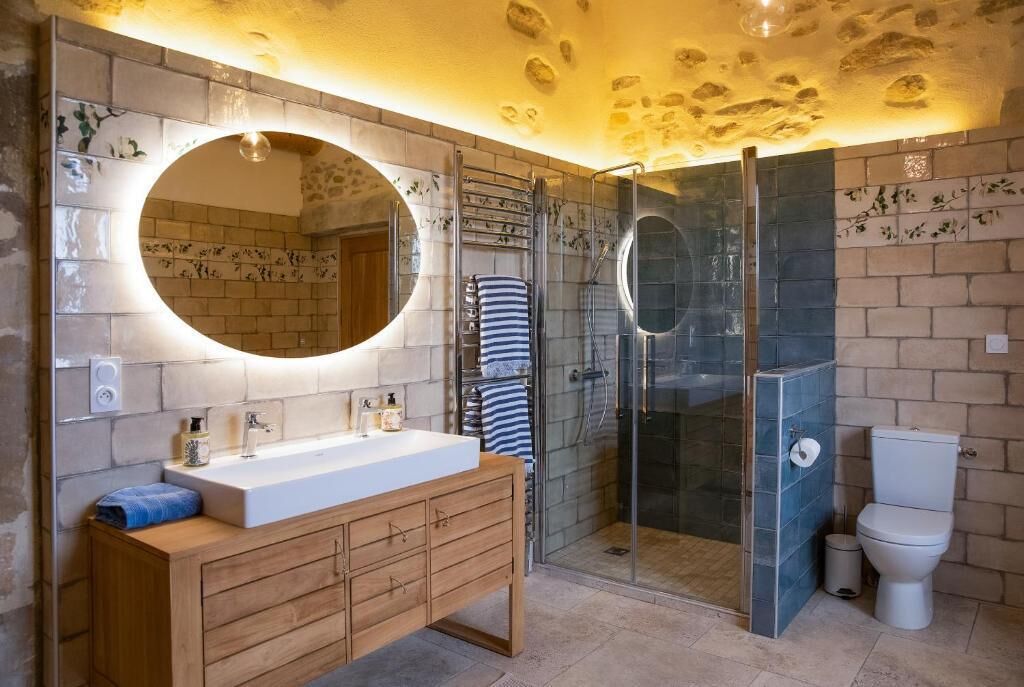 Une salle de bain moderne avec un meuble-lavabo en bois, un grand miroir, une douche en verre et des toilettes.