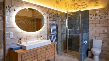 A modern bathroom with a wooden vanity, a large mirror, a glass shower enclosure, and a toilet.