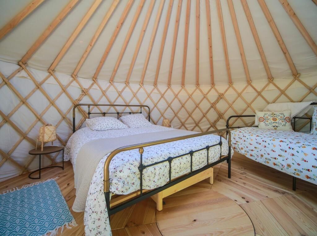 A cozy interior of a yurt with a bed and a smaller sleeping area.