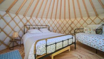 A cozy interior of a yurt with a bed and a smaller sleeping area.