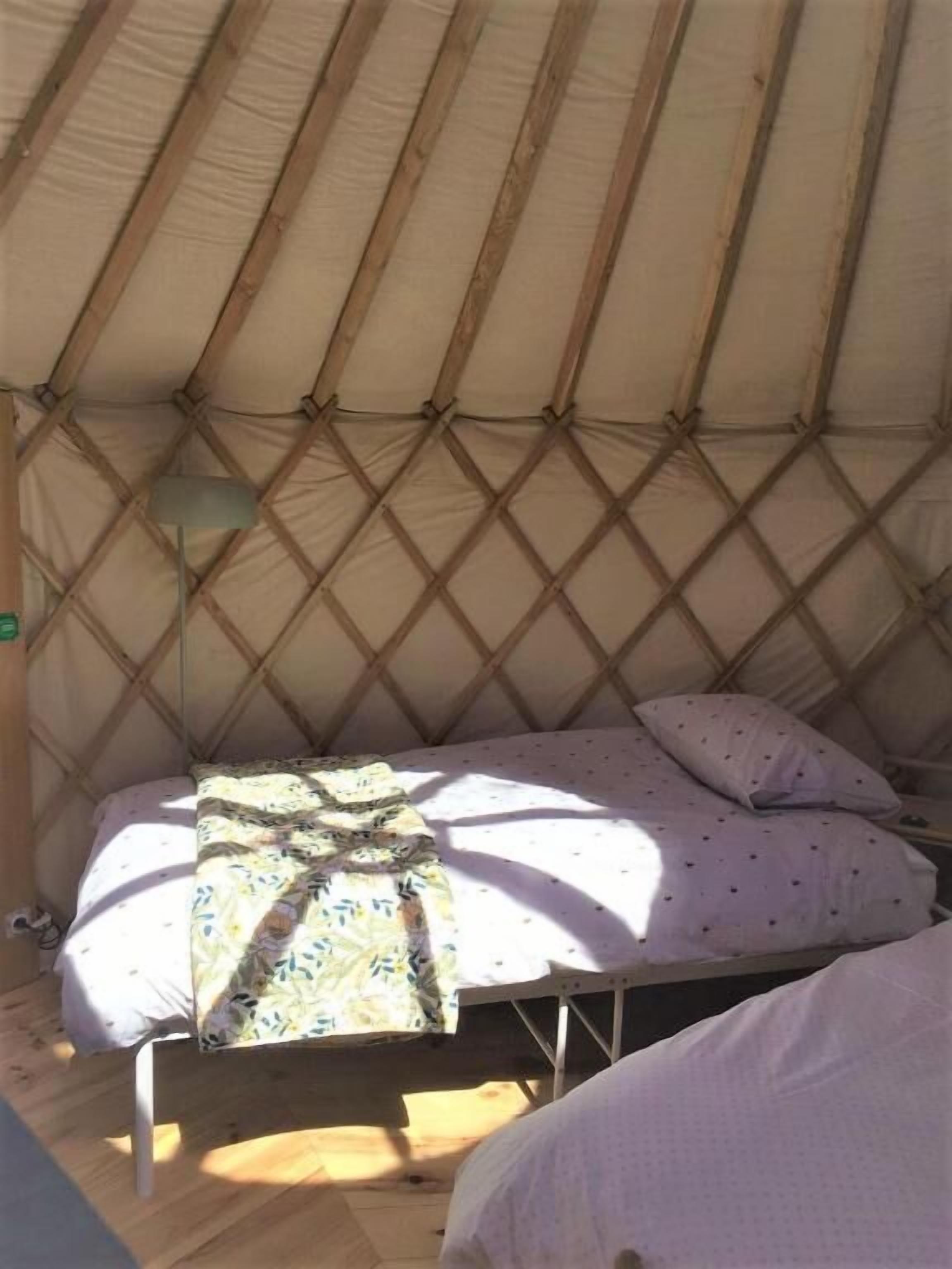 Una cama individual en una yurtas con una colcha y almohadas estampadas.