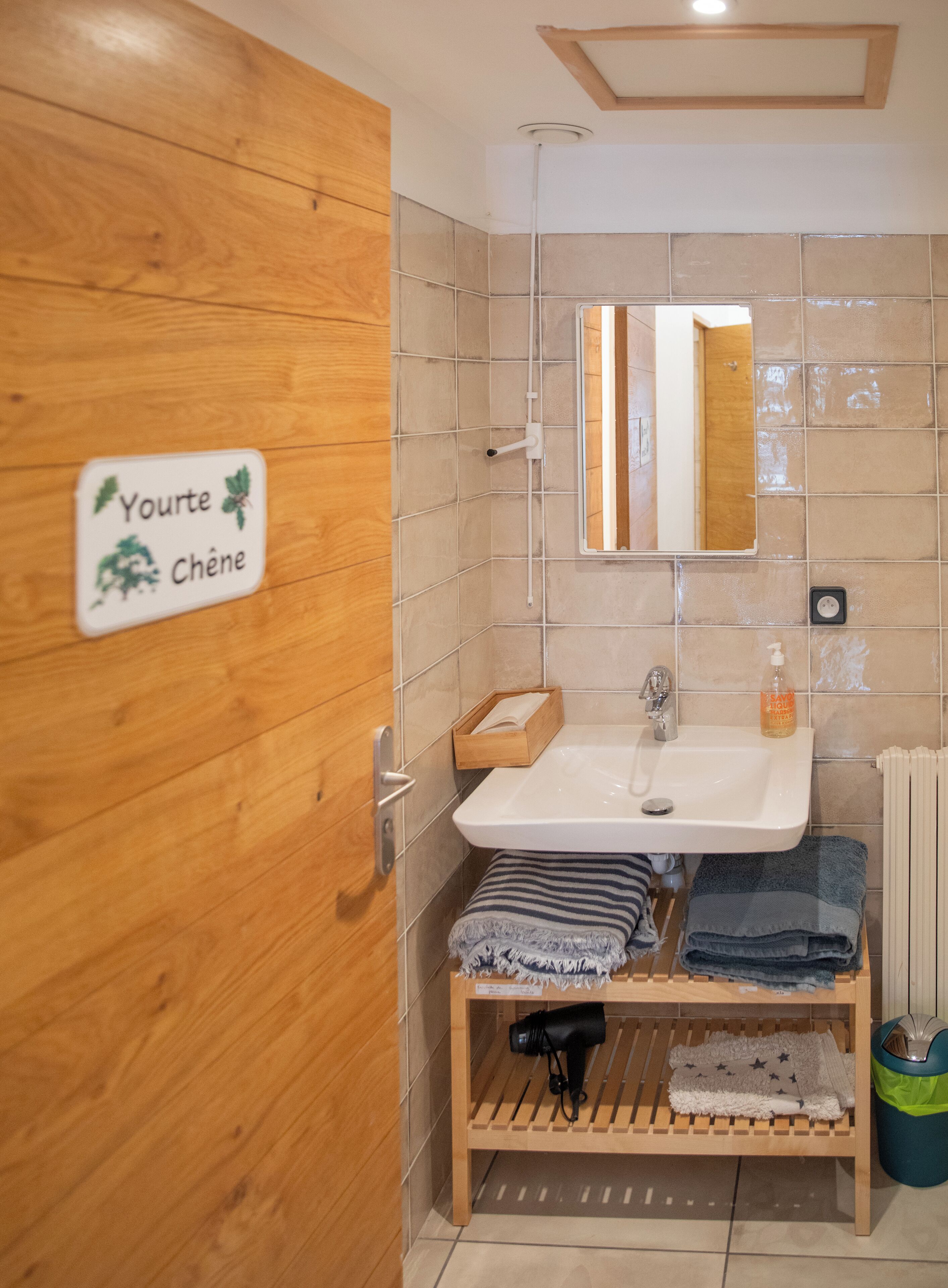 Een badkamer met een houten deur, een wastafel, een spiegel en een handdoekhouder.