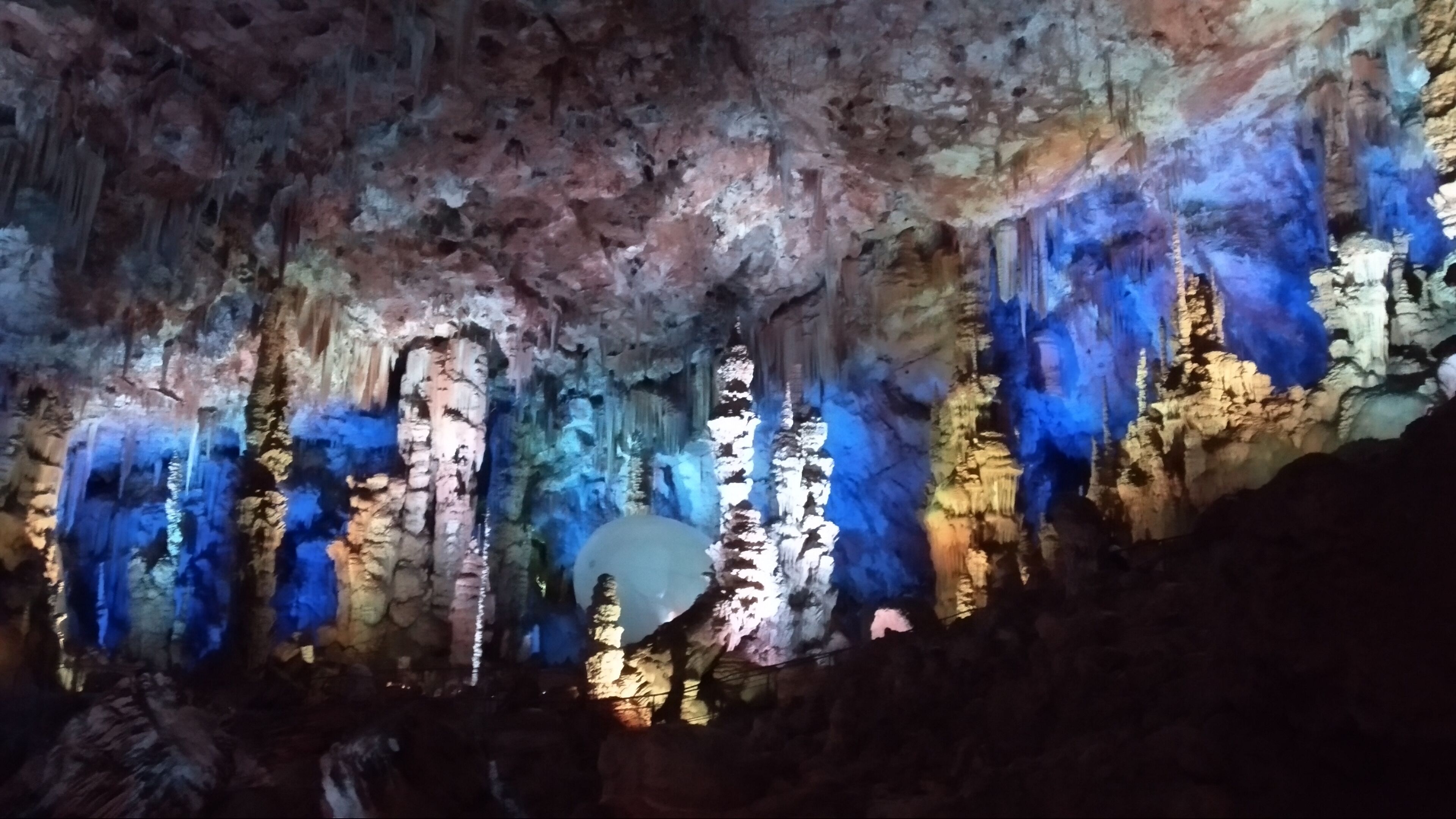 Une grotte ornée de stalactites et de stalagmites, éclairée par un système d’éclairage artificiel.