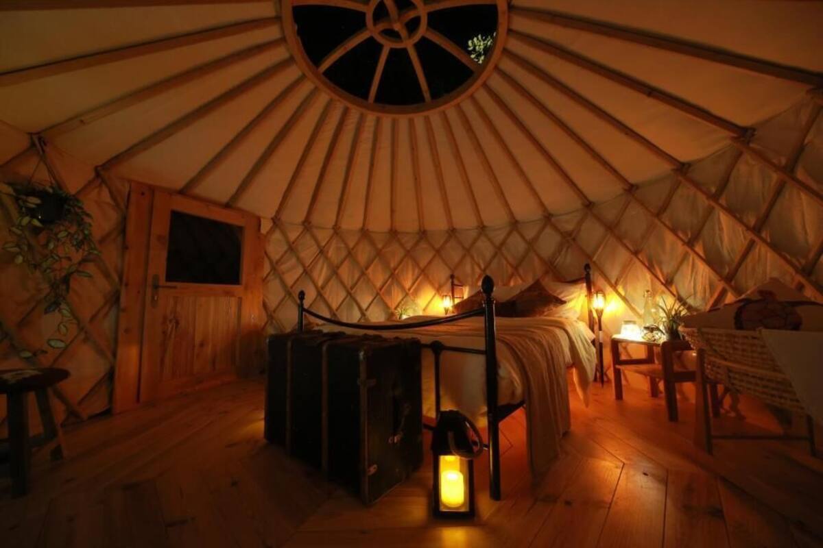 Interior acogedor de una yurta con una cama, un farol y un armario de madera.