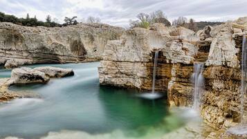 Un paysage naturel comprenant une cascade, des formations rocheuses et un bassin d’eau limpide.
