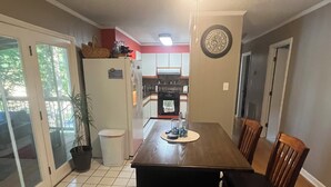A compact kitchen with a dining table, chairs, and a refrigerator. - The Shamrock Lake Norman. Swim, fish, kayak, boating, pool, hot tub, jet ski. (Statesville)