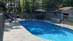 A swimming pool with a wooden deck, a small dog, and a covered patio area. - The Shamrock Lake Norman. Swim, fish, kayak, boating, pool, hot tub, jet ski. (Statesville)