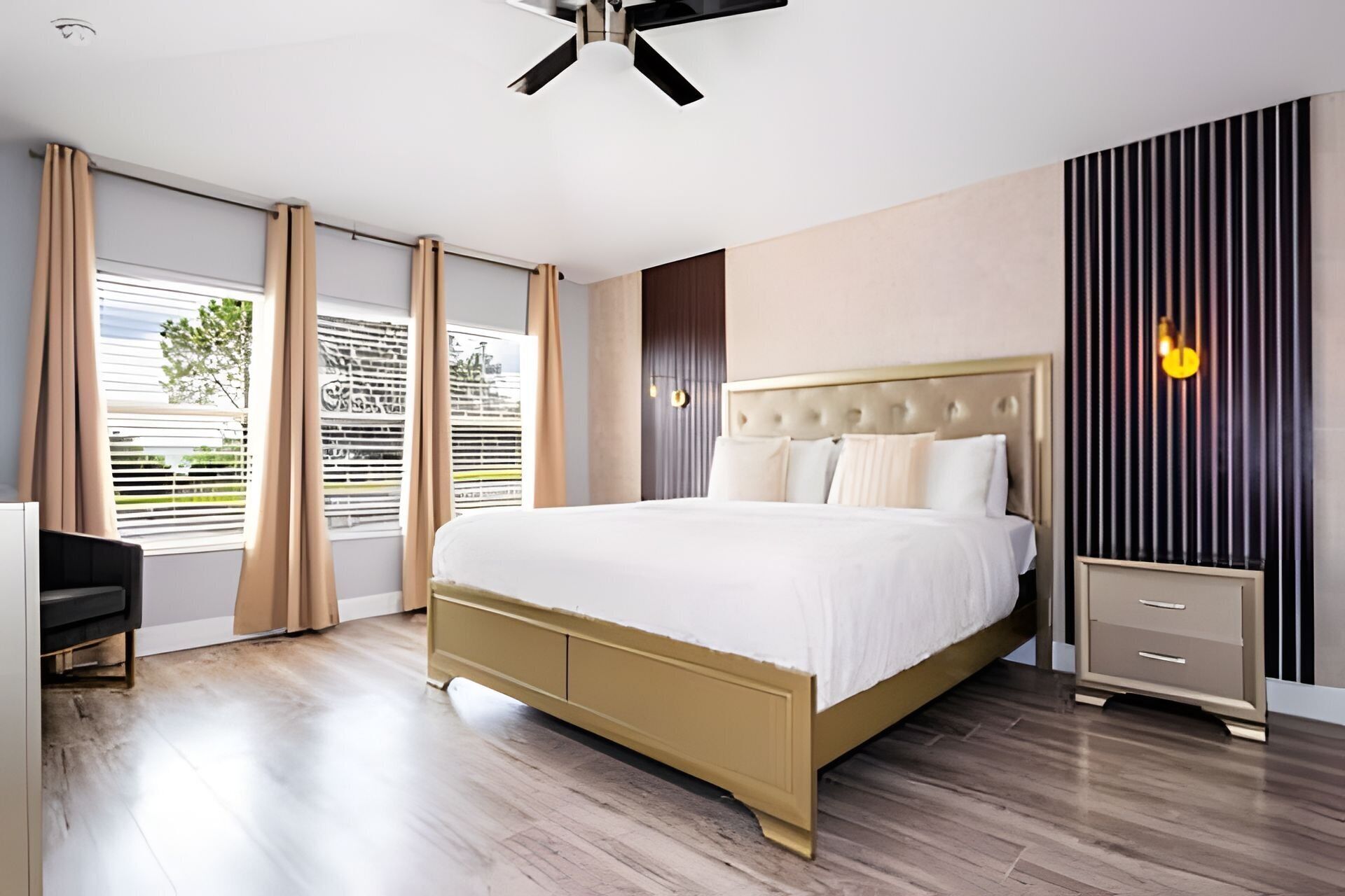A modern bedroom with a large bed, a bedside table, a wardrobe, and a ceiling fan.