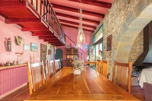 Un comedor con una mesa de madera, sillas, un muro de piedra y una escalera.