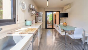 Eine moderne Küche mit Holztresen, Spüle aus Edelstahl und einem Glastisch mit weißen Stühlen.