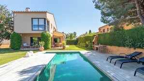 Ein modernes, zweistöckiges Haus mit Swimmingpool, Gartenmöbeln und einem gepflegten Garten.