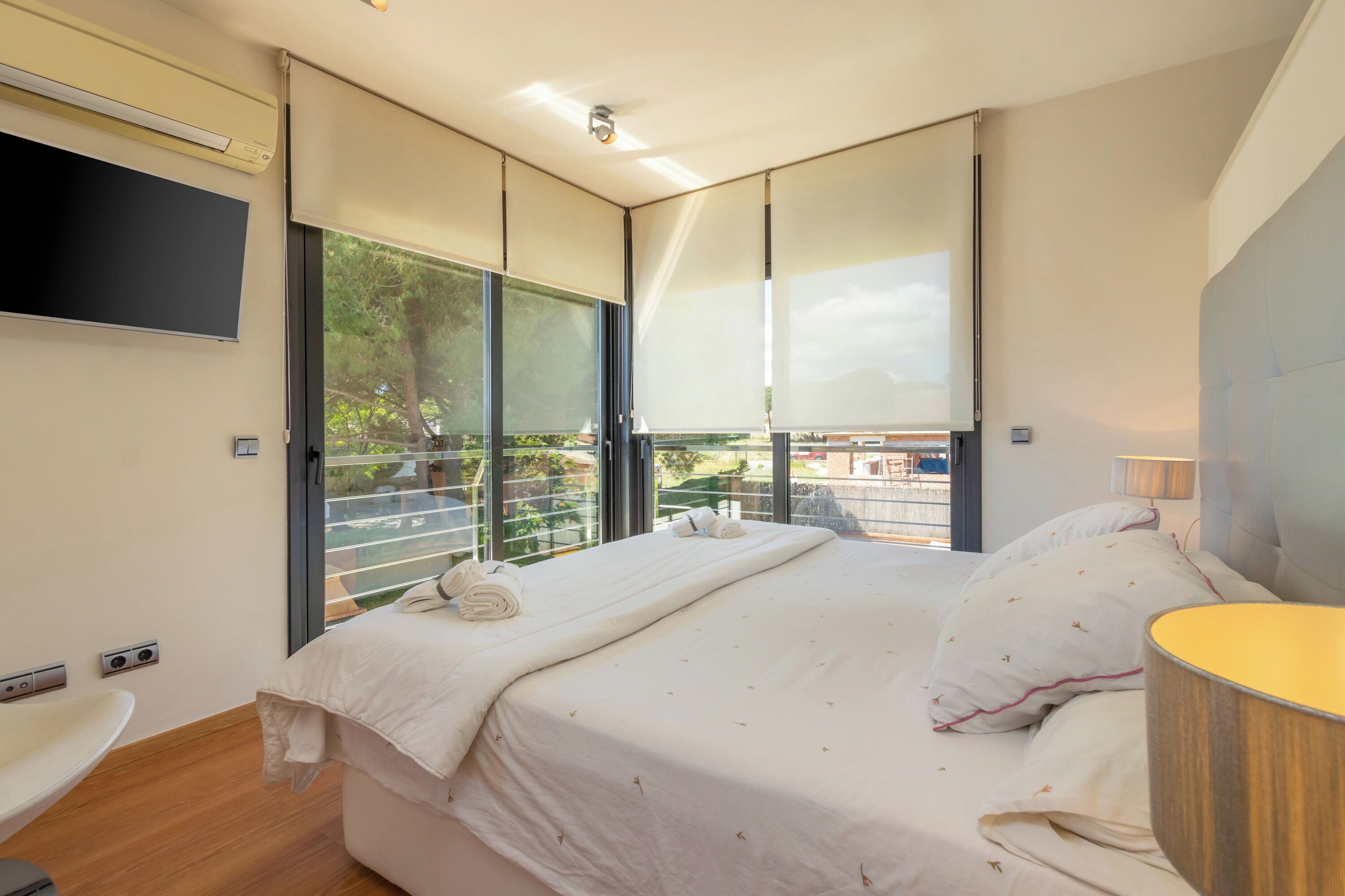Ein modernes Schlafzimmer mit einem großen Bett, einem Flachbildfernseher und einem Balkon mit Blick.