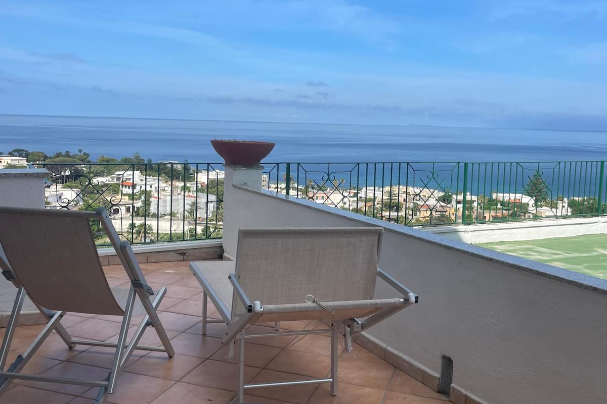 Un balcon avec deux chaises, une petite table et une vue sur la mer.