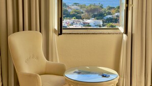 A room with a view of the sea, a beige armchair, and a small table with a magazine. - Parco dei Principi Resort & Spa (Forio)