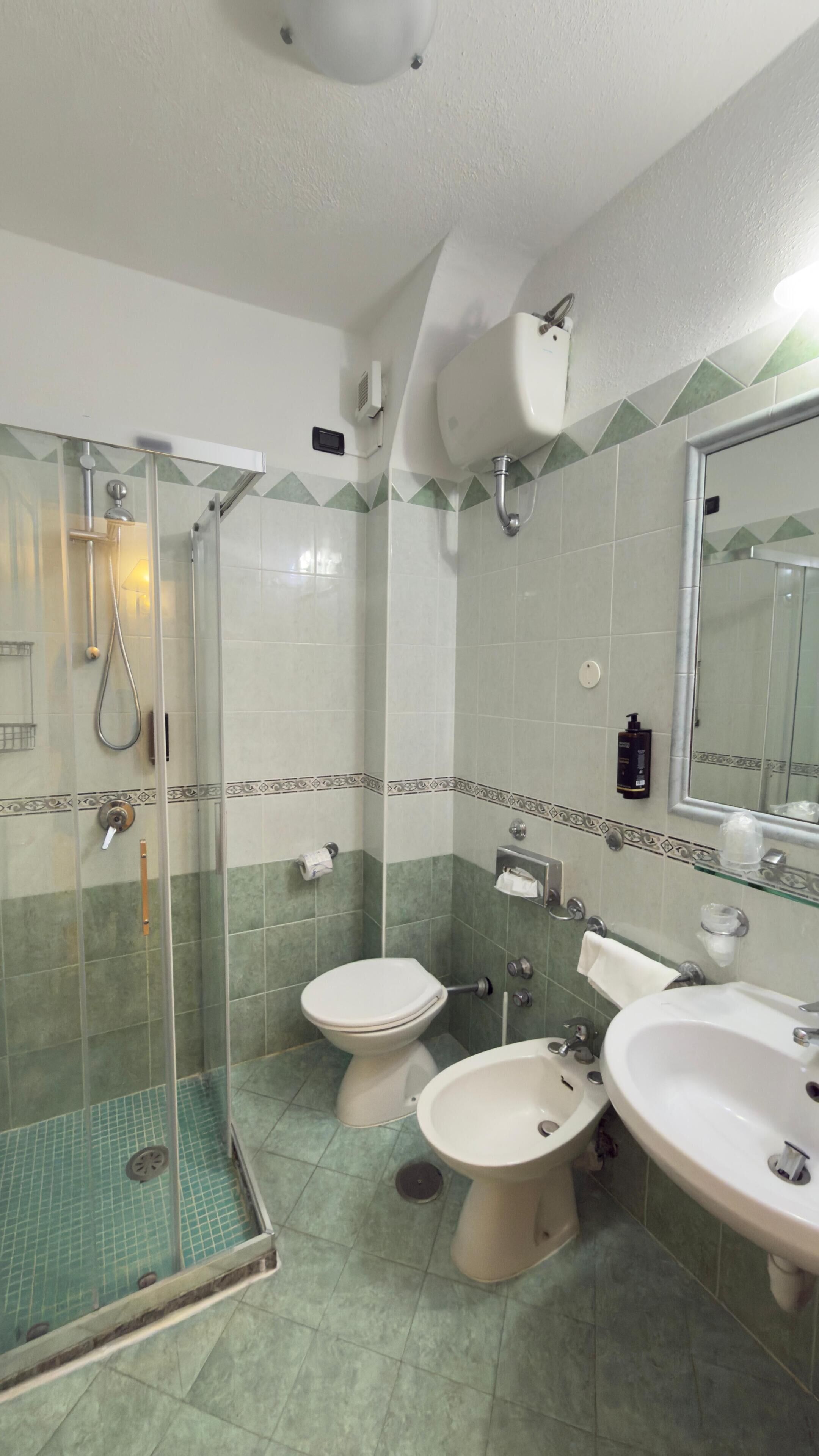 Une salle de bain avec une douche à parois de verre, deux toilettes et deux lavabos.