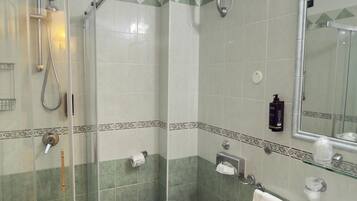 Une salle de bain avec une douche à parois de verre, deux toilettes et deux lavabos.
