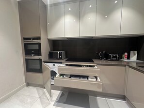 A modern kitchen with built-in appliances, including a microwave, oven, and dishwasher, and a stainless steel countertop. - 3 Bedroom Apartment at Edgware Rd Westchester House (London)