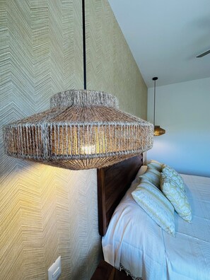 A room with a woven hanging light fixture, a bed with pillows, and a patterned wallpaper. - Oceanview Pavilion Bucerías. 2BR. New Listing - Check In to the Extraordinary! (Bucerías)