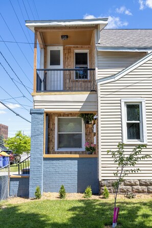 A two-story house with a balcony, a window with a view, and a small tree in the front yard. - Westside 4 Bedroom 2 Bath Furnished Remodeled. Close to Bridge St GR City. (Grand Rapids)