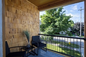 Un balcon en bois donnant sur une rue et des arbres.