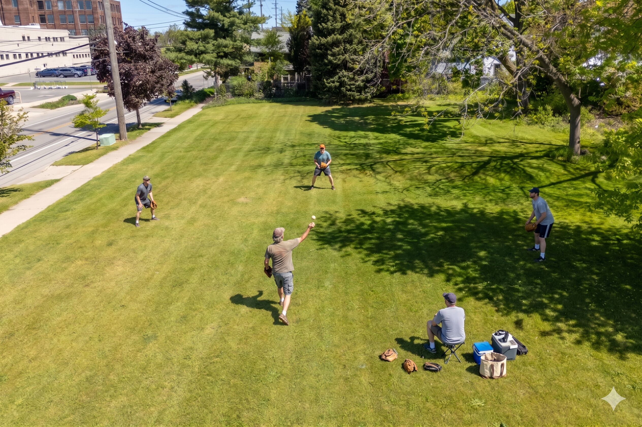 A grassy outdoor area with people playing, a road, and buildings in the background.