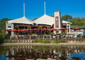 A waterfront restaurant with outdoor seating and a view of the water.
