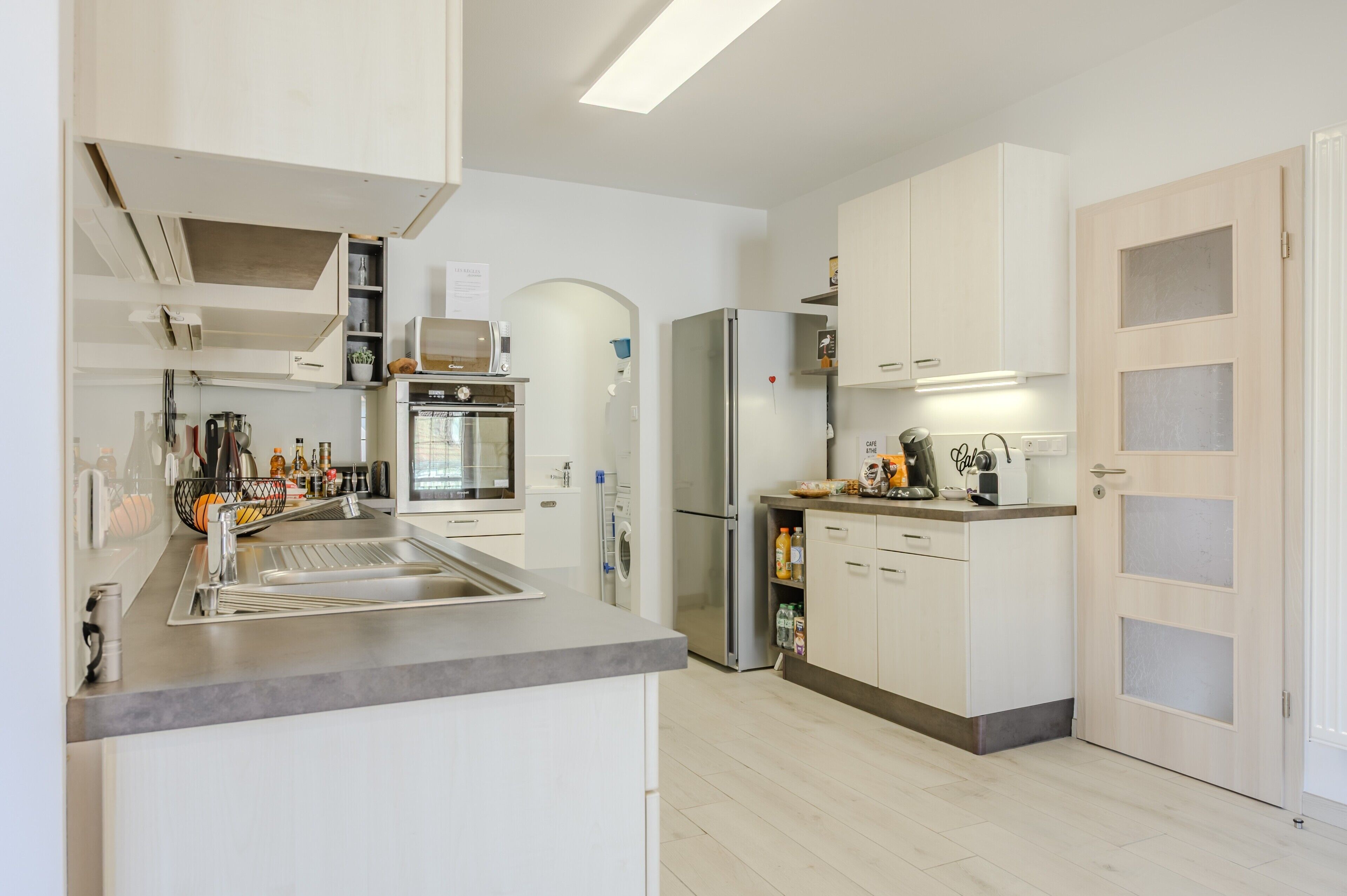 A modern kitchen with stainless steel appliances, white cabinetry, and a built-in oven.
