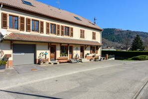 Un edificio a due piani con tetto in tegole, un garage e un portico d'ingresso con gradini.