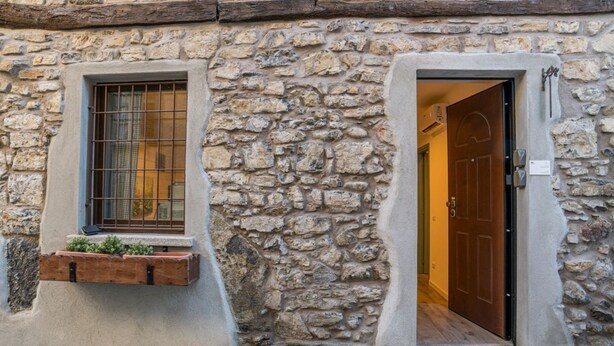 A stone building with a wooden door and a window with a metal grille. - GuestHost - Cozy 35 sqm apartment, perfect for four people, located on the ground floor of a building (access via one step).The property is located in Visgnola, a quiet village near Bellagio, one of Lake Como's most popular destinations. It's well-served (Bellagio)