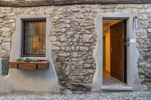 Un edificio de piedra con puerta de madera y ventana con reja de metal.