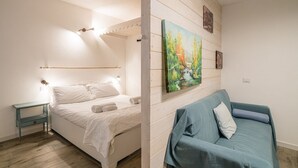 A bedroom with a bed, a nightstand, a painting, and a sofa. - GuestHost - Cozy 35 sqm apartment, perfect for four people, located on the ground floor of a building (access via one step).The property is located in Visgnola, a quiet village near Bellagio, one of Lake Como's most popular destinations. It's well-served (Bellagio)