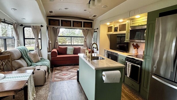 Un intérieur de camping-car compact comprenant un coin cuisine, un espace repas et un salon.