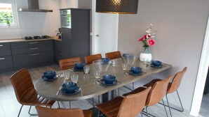 Une cuisine moderne avec une table à manger pour six personnes, entourée de chaises marron.