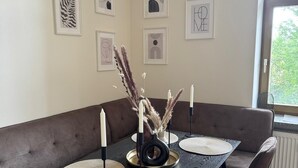 Un coin repas avec une table en bois foncé, six chaises et un canapé marron.