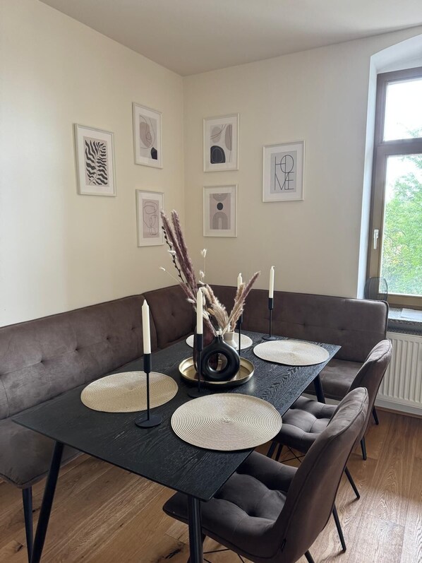 Un coin repas avec une table en bois foncé, six chaises et un canapé marron.
