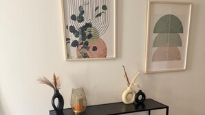 Une console noire dotée de trois étagères, un tapis blanc et deux œuvres d’art encadrées accrochées au mur.