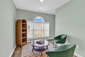A room with a large window, a chess table, a green chair, and a wooden bookshelf. - NEW! 2 min walk to Beach + 2 King Master Suites + Family Friendly (Surfside Beach)