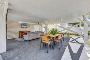Eine Terrasse im Freien mit Esstisch, Stühlen, einer Couch und einem Deckenventilator.