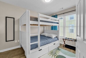 Ein Etagenbett mit Stauraumschublade, ein Fenster mit Jalousien und eine Tür mit Fußmatte.