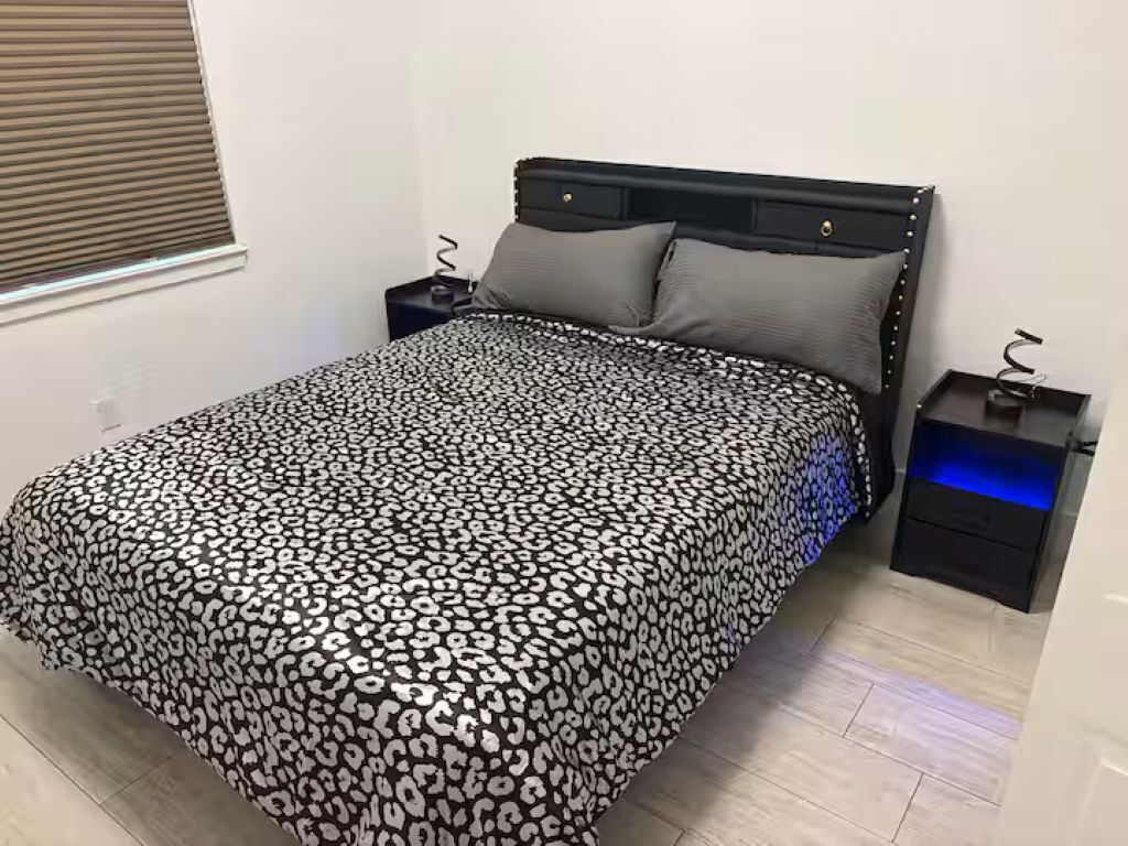 A bedroom with a bed, a nightstand, and a drawer unit.
