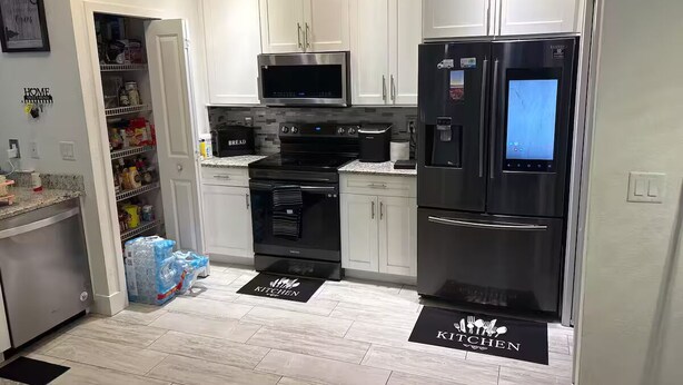 Una cucina moderna con mobili bianchi, elettrodomestici in acciaio inossidabile e un forno a microonde.