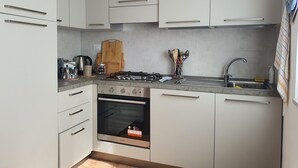 Une cuisine moderne avec des meubles blancs, une cuisinière à gaz, un four et un évier.