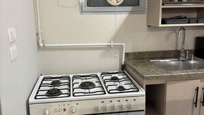 Une cuisine équipée d’une cuisinière à gaz, d’un four et d’une petite fenêtre de ventilation.