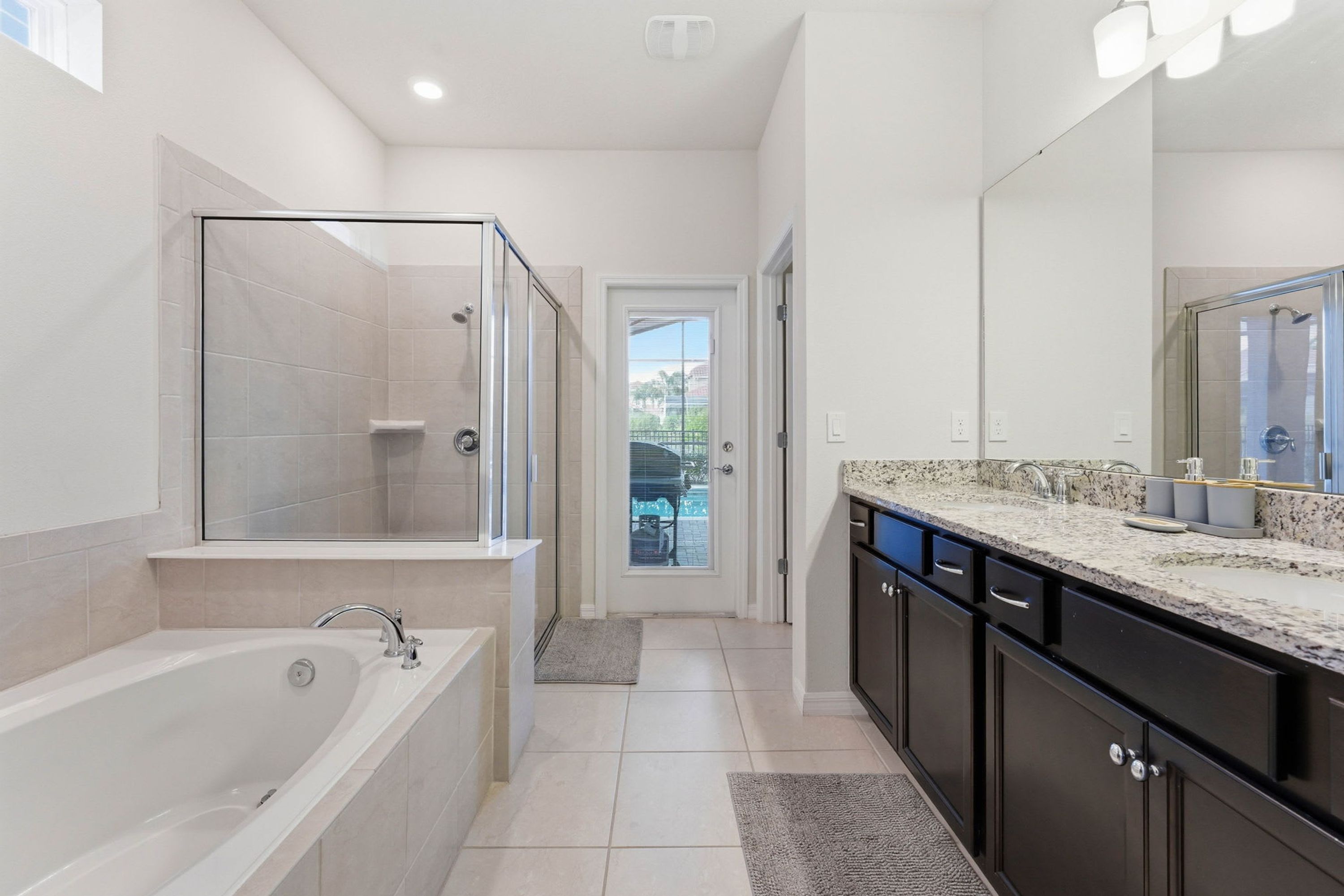 Un baño moderno con cabina de ducha de vidrio, una bañera independiente y un espejo grande sobre el lavamanos.